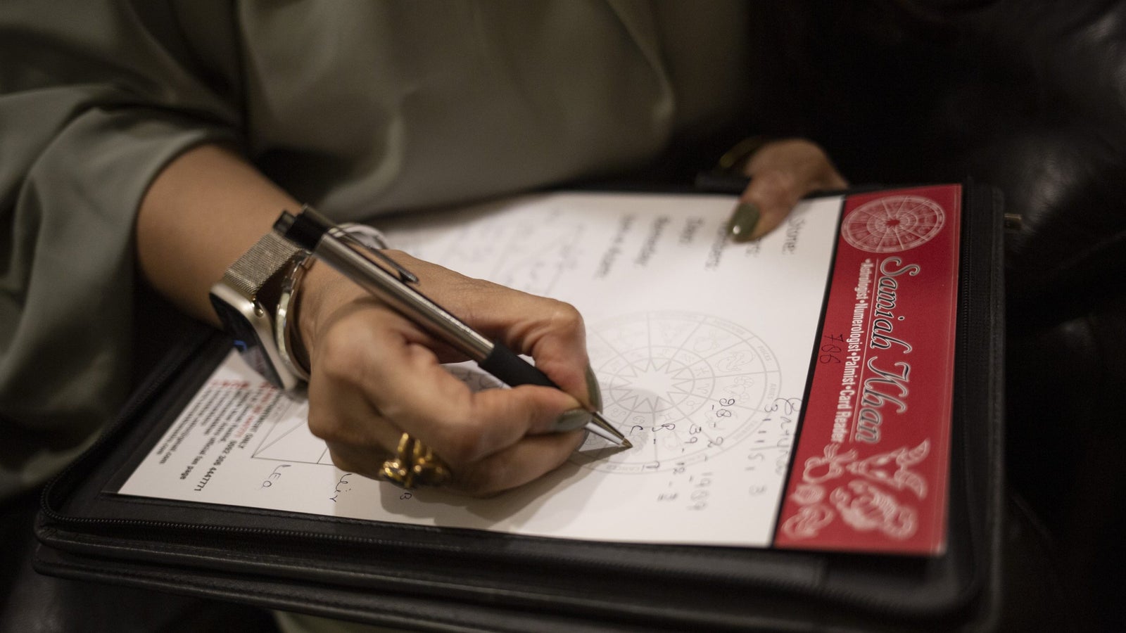 A photograph showing a woman's hand writing on a piece of paper.