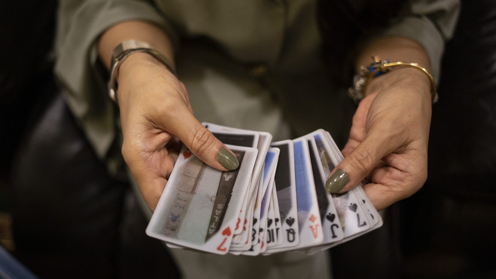 A photograph showing a woman's hands displaying a set of playing cards.