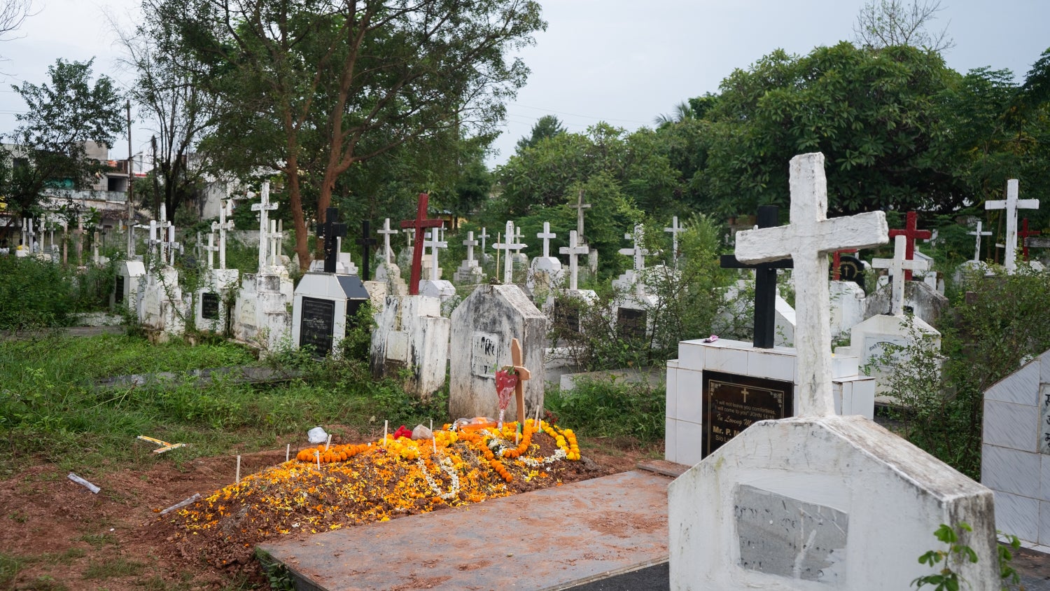 A photo of a Christian cemetery with flowers placed on one of the graves.