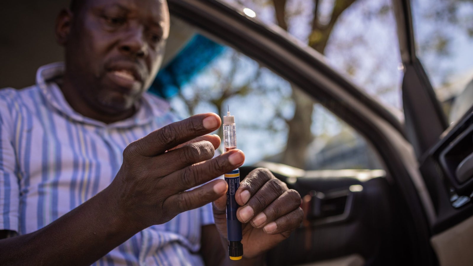 Teddy Dube checks a medical syringe while seated in his car seat.