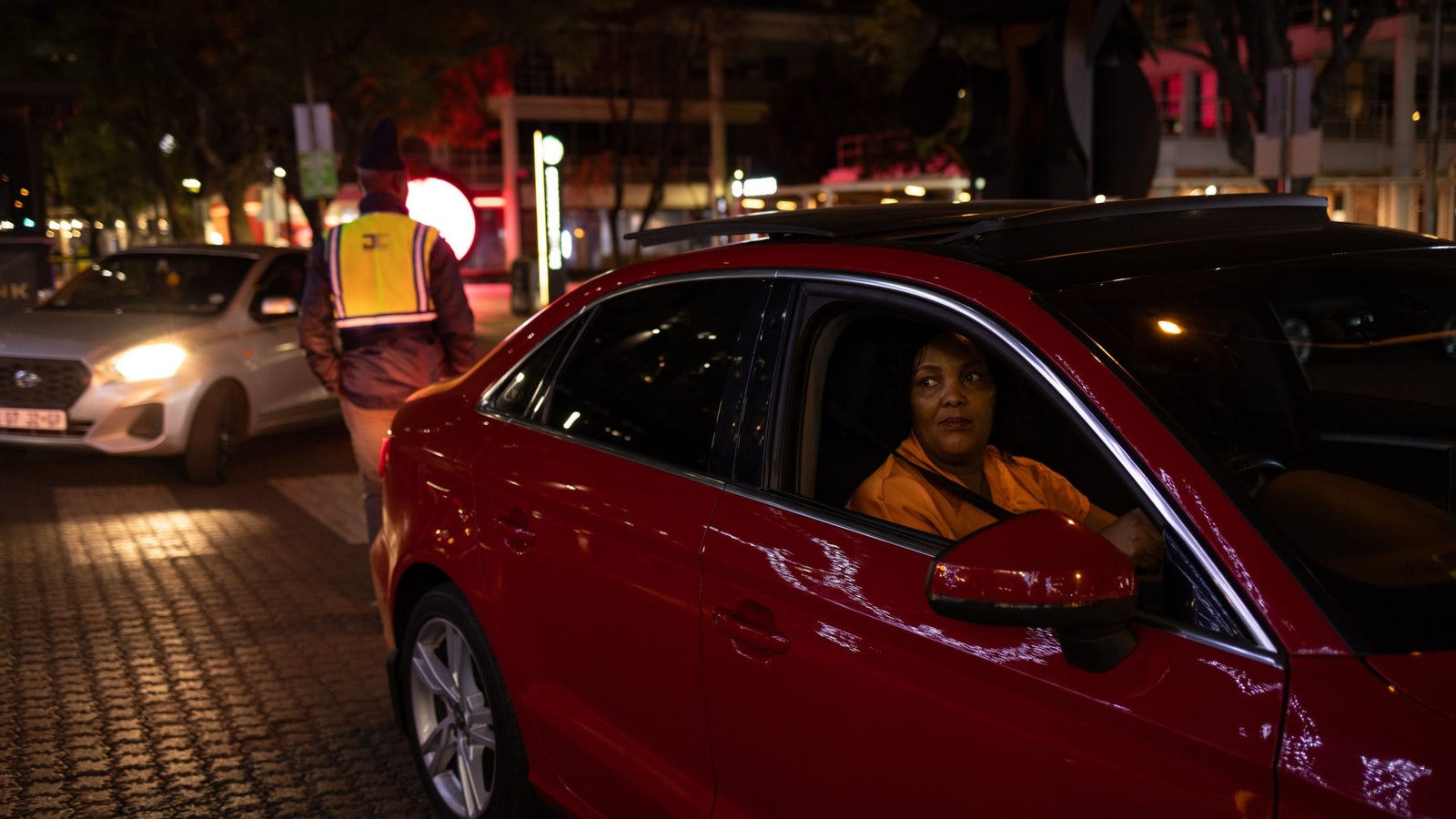 Uber driver Nolwazi Mtshekexe in her shiny red car on the street of Johannesburg at night.