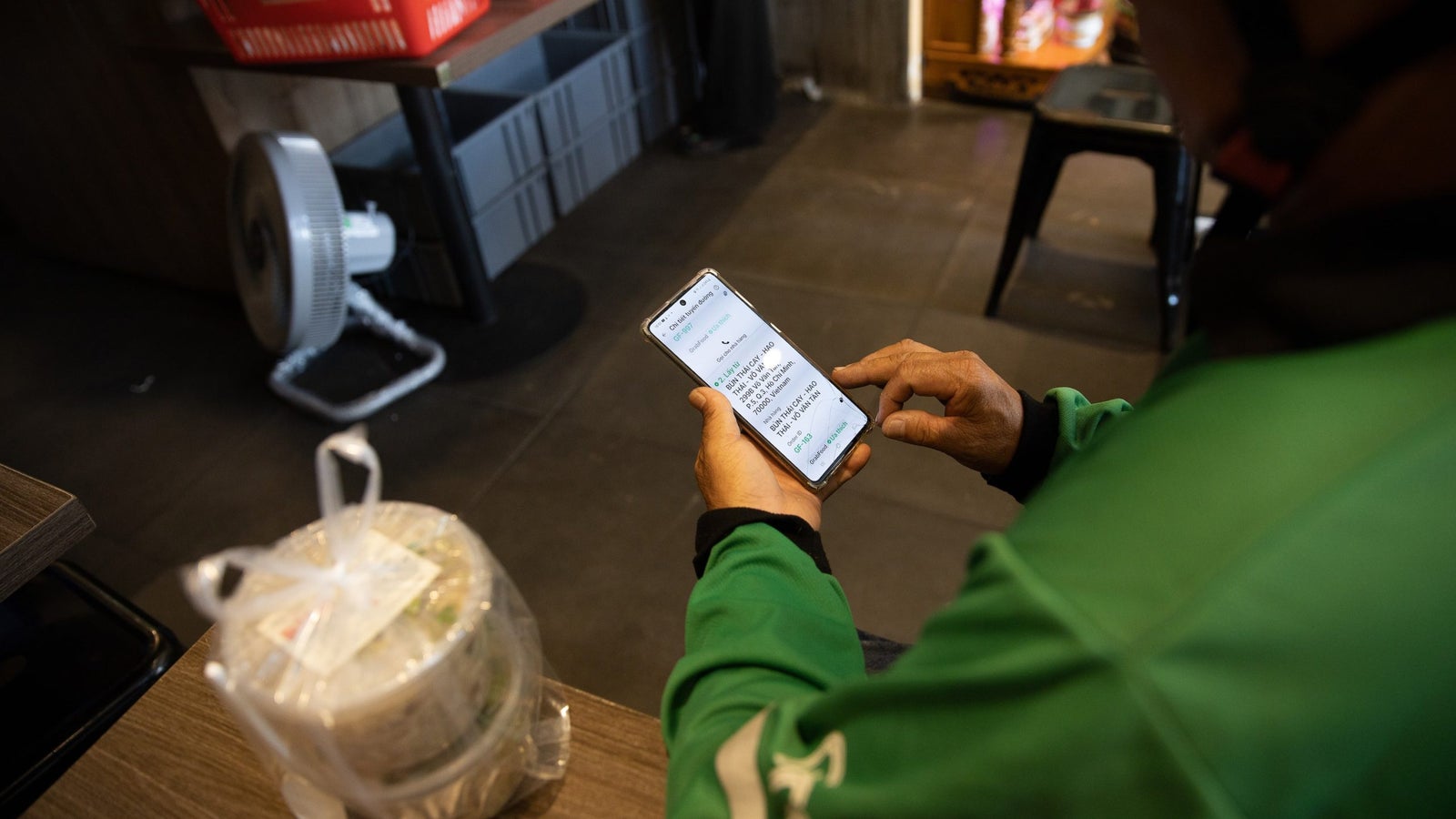 Grab driver Nguyen Van Sau uses his phone while seated at a restuarant.