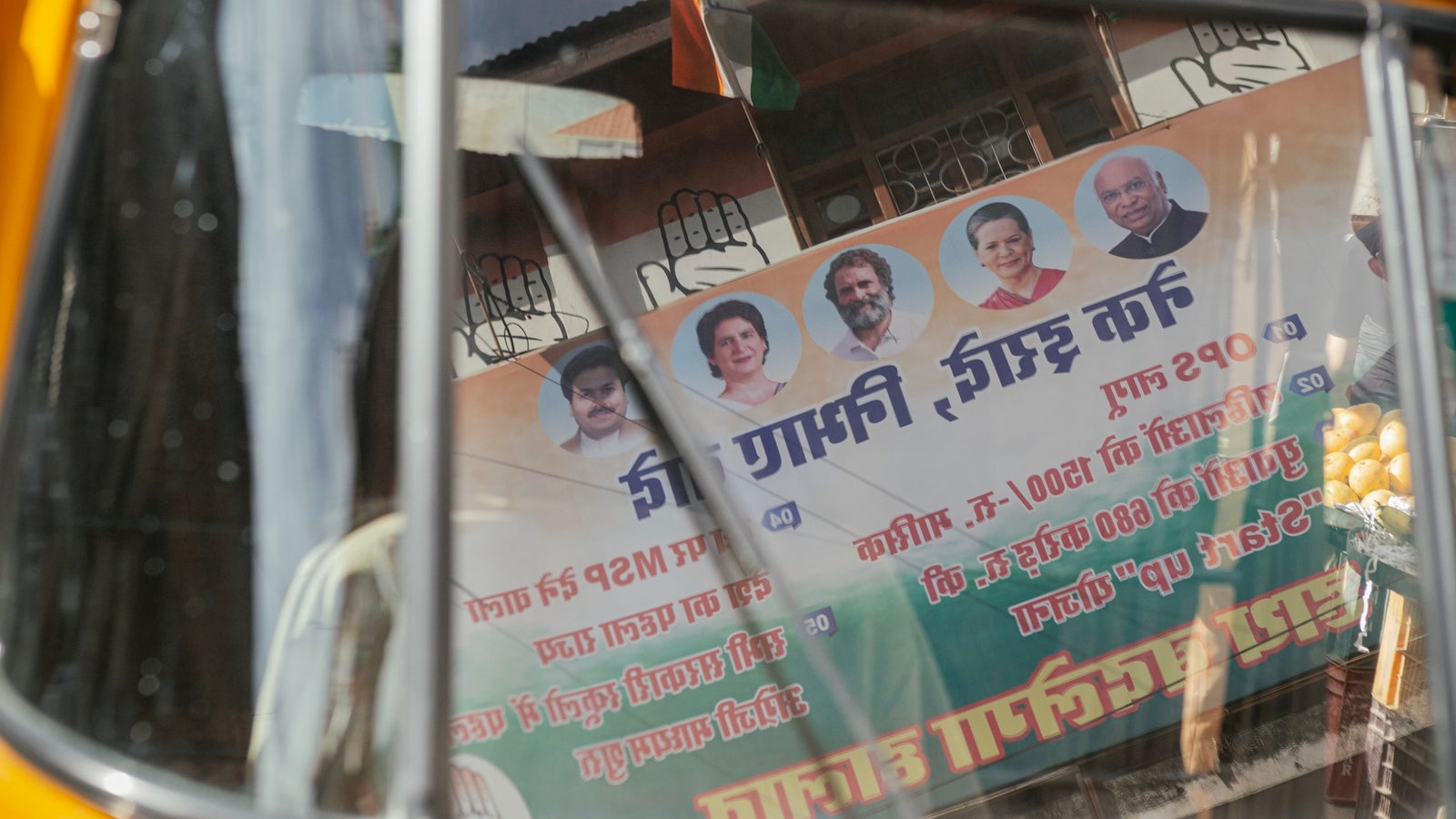 A photography showing an Indian political poster reflected in the window of a rickshaw.