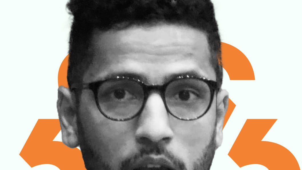 A photo of Raqib Hameed Naik against an orange diacritic background.