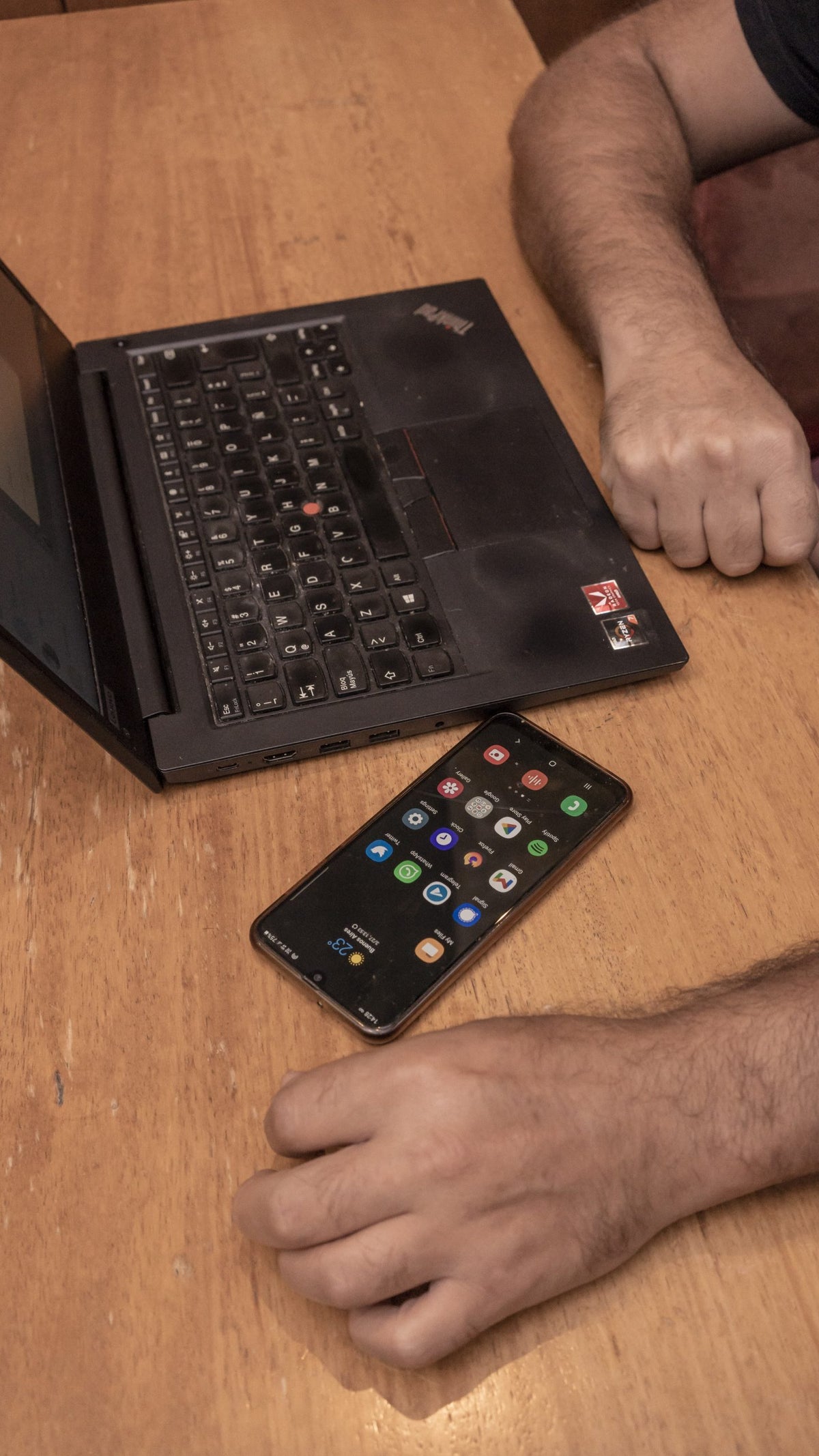 A photo of computer programmer Javier Smaldon's hands, computer, and phone while seated at a table in Argentina.
