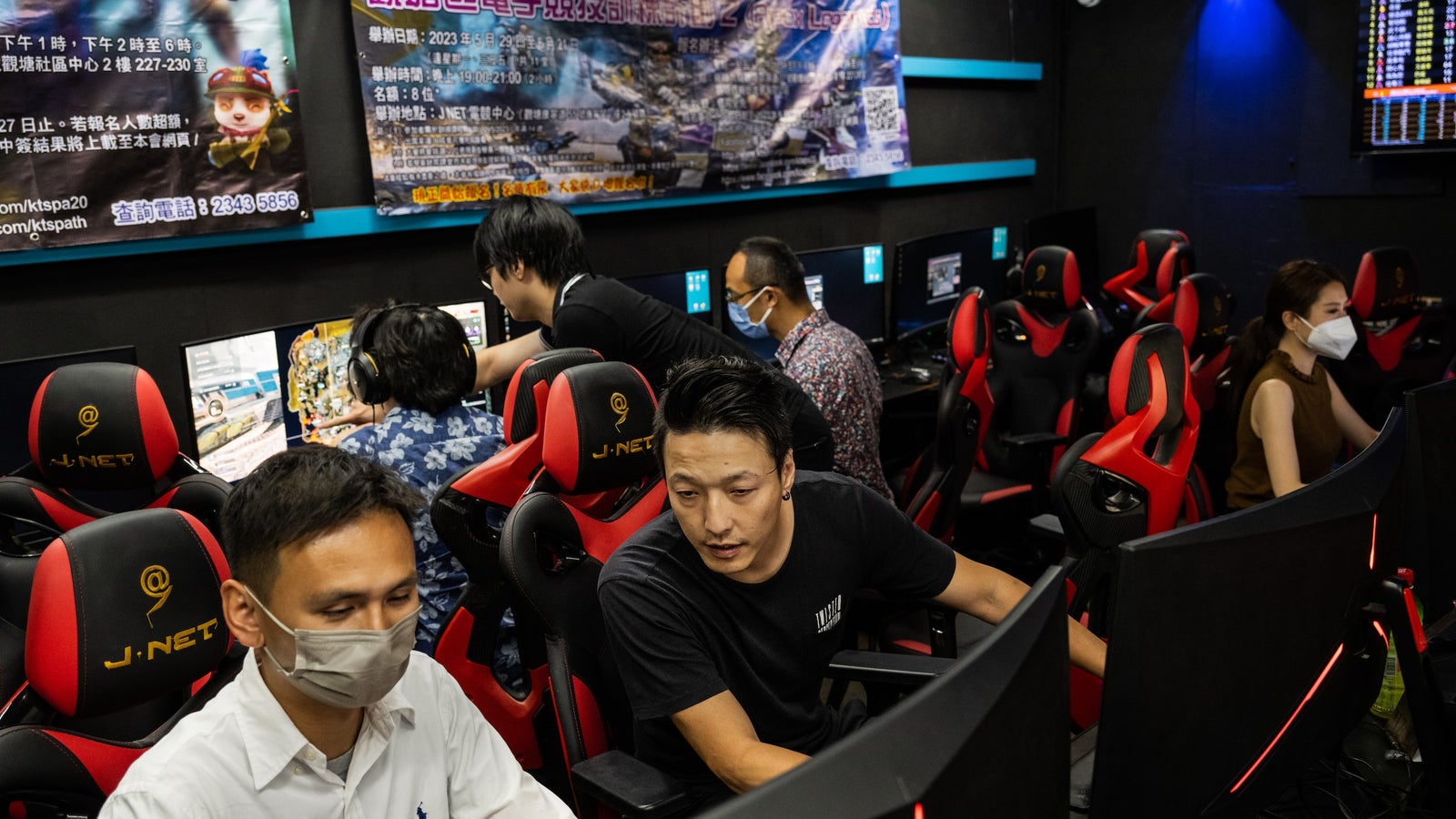 A photo of people sitting at rows of computers in a dark room.