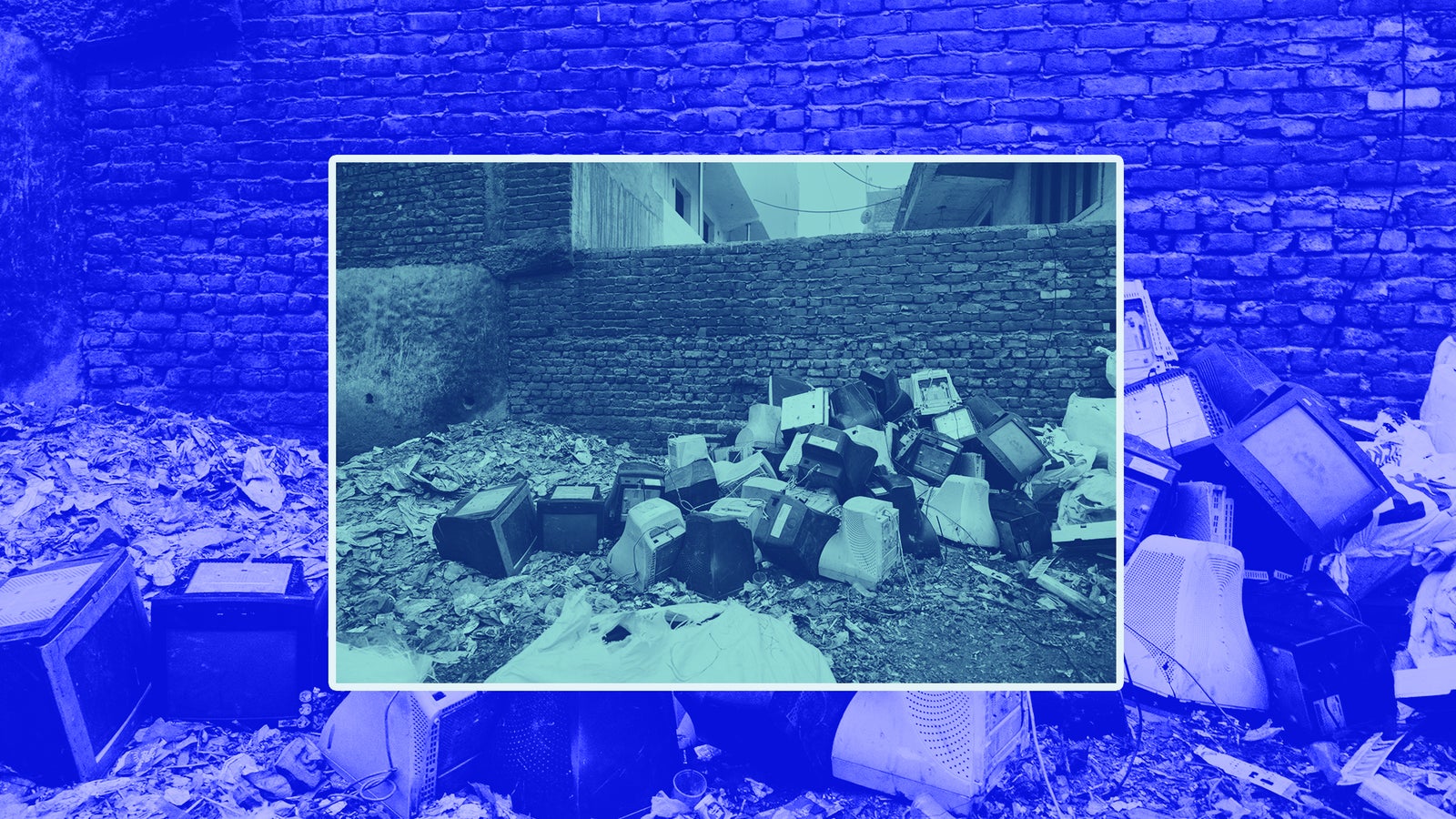 A pile of old, discarded televisions surrounded by garbage near a brick wall.