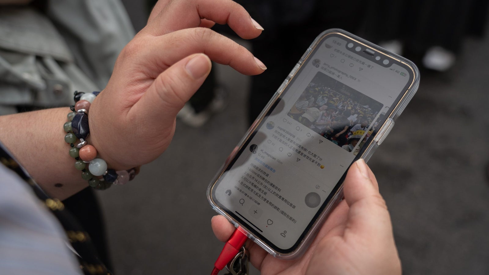 A close up photograph showing a person holding a mobile phone in their hand and about to tap on it with their left hand.