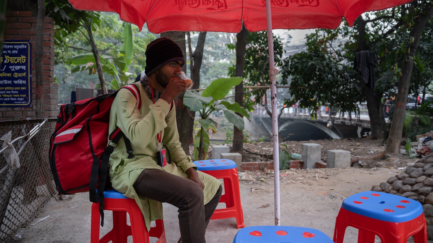 A RedX delivery rider sips tea on a break at a road side tea stall.