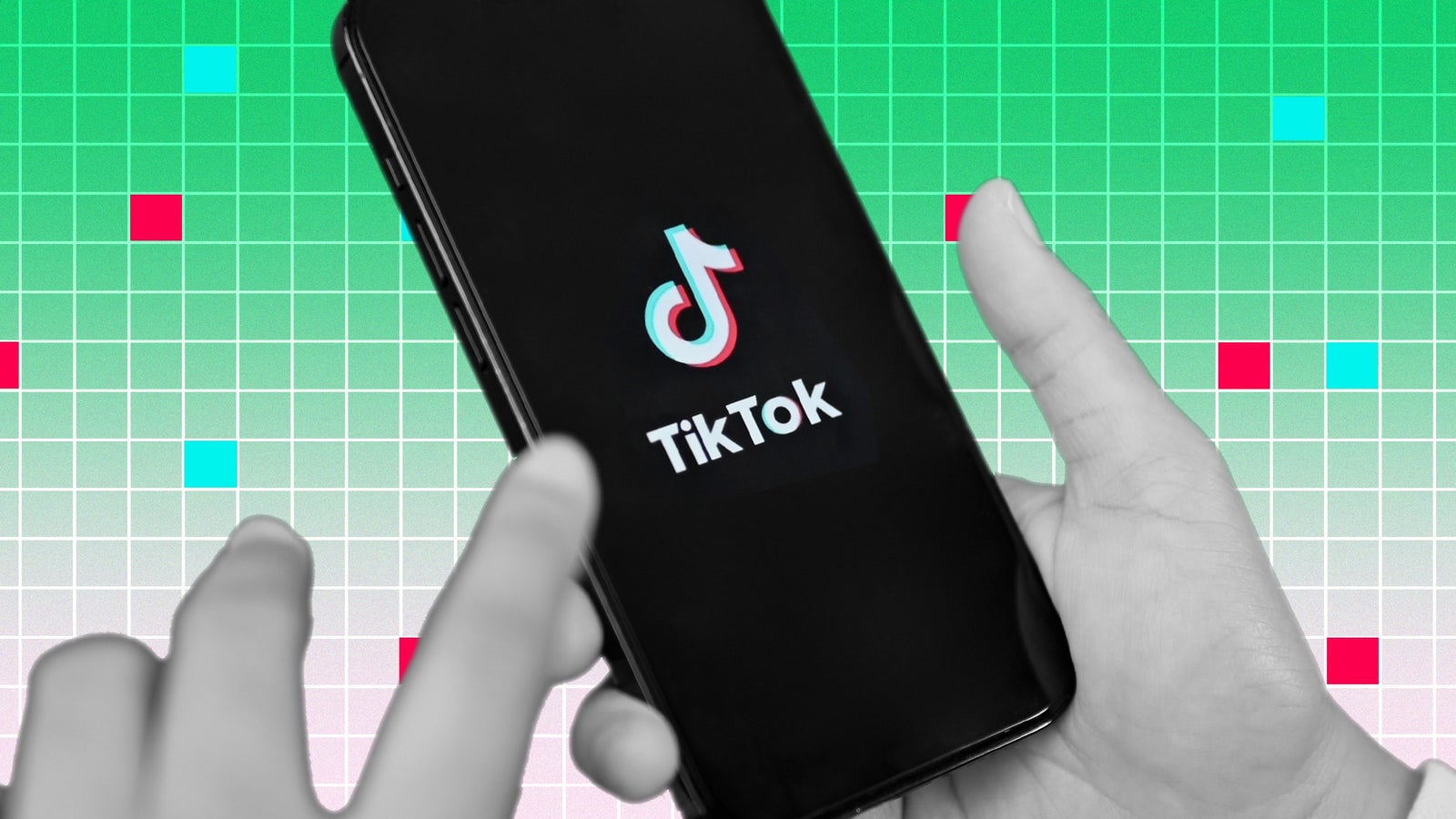 A photo illustration showing black and white hands holding a mobile phone with the TikTok logo and name displayed on a black screen. The background of the image is a pattern of small green squares and a few colored with the pink and aqua colors used by the TikTok logo.