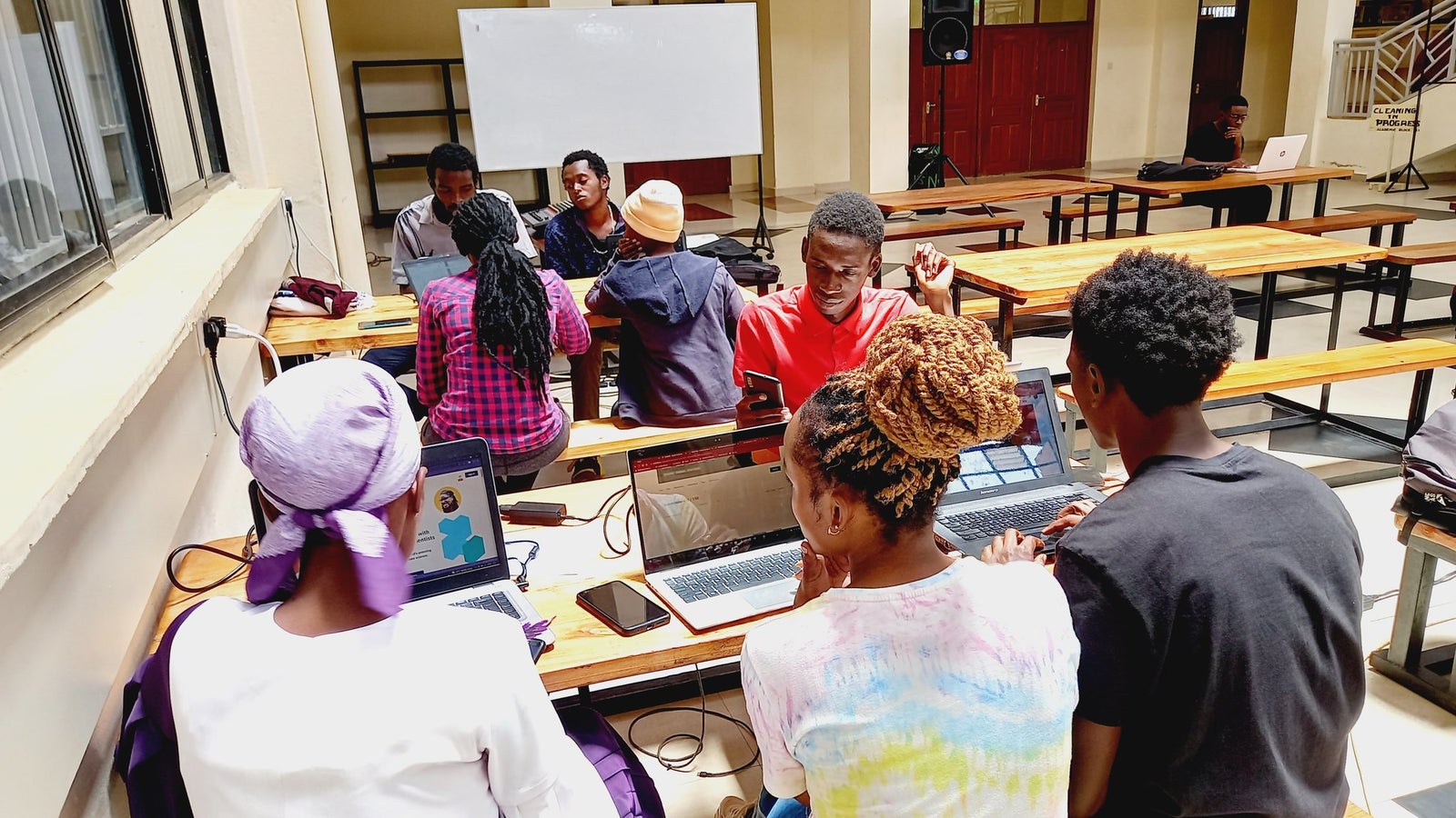 A photograph showing people seated in a classroom working on computers.