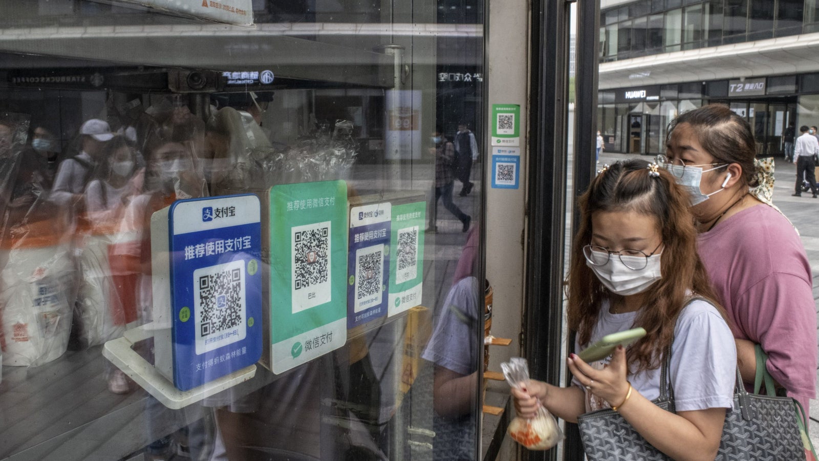 A photo of two women standing next to a window displaying QR codes
