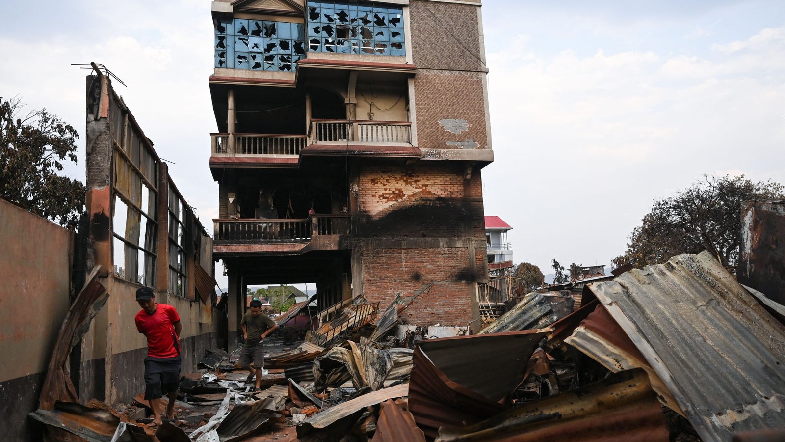 A photo showing two men walking through the wreckage of a burnt building.