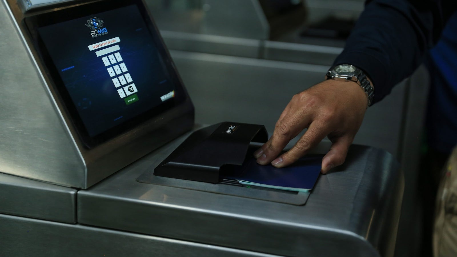 A person scans their passport at a Colombian immigration center.