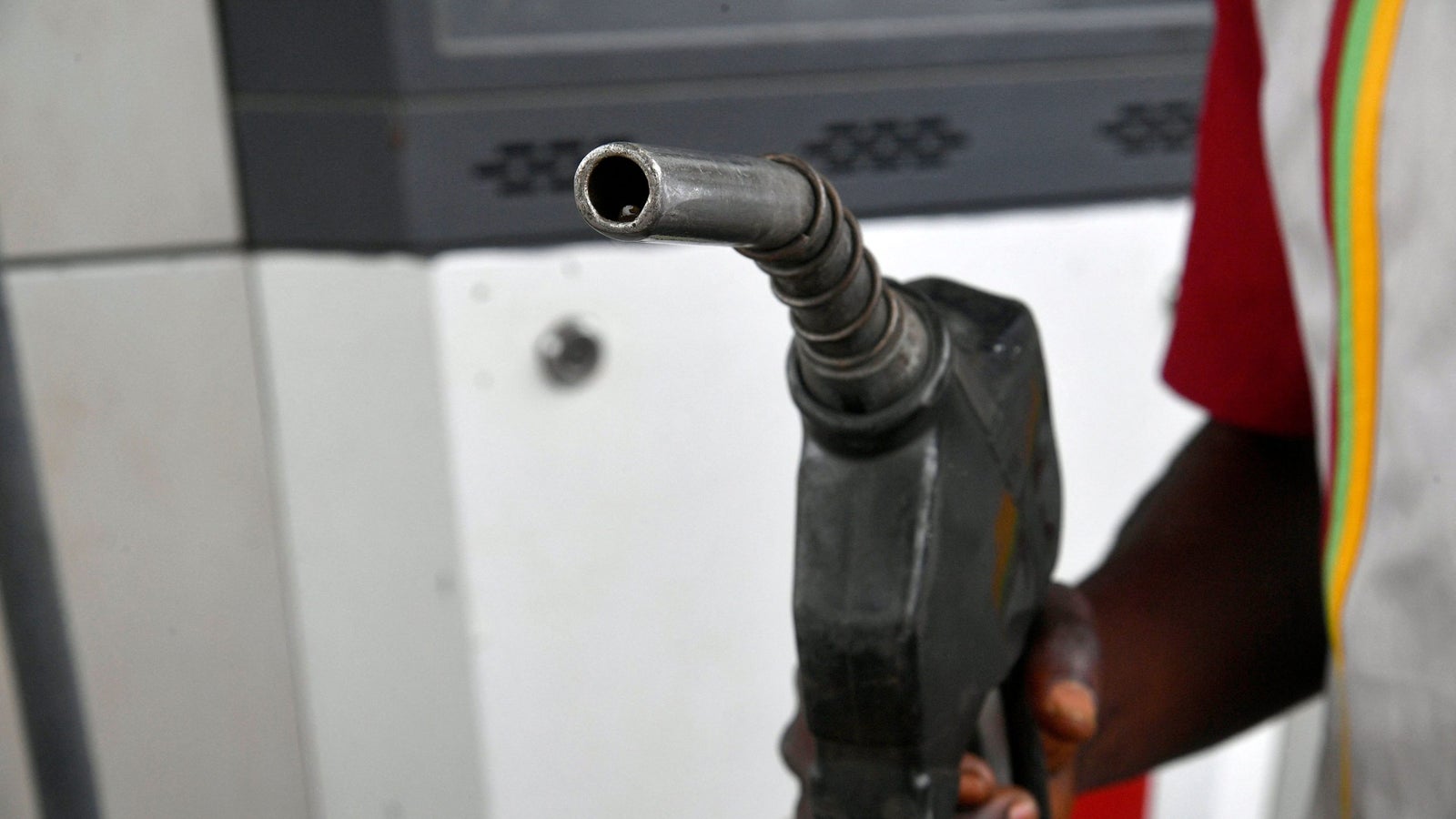 A photo showing the tip of a fuel pump nozzles being held by a hand.