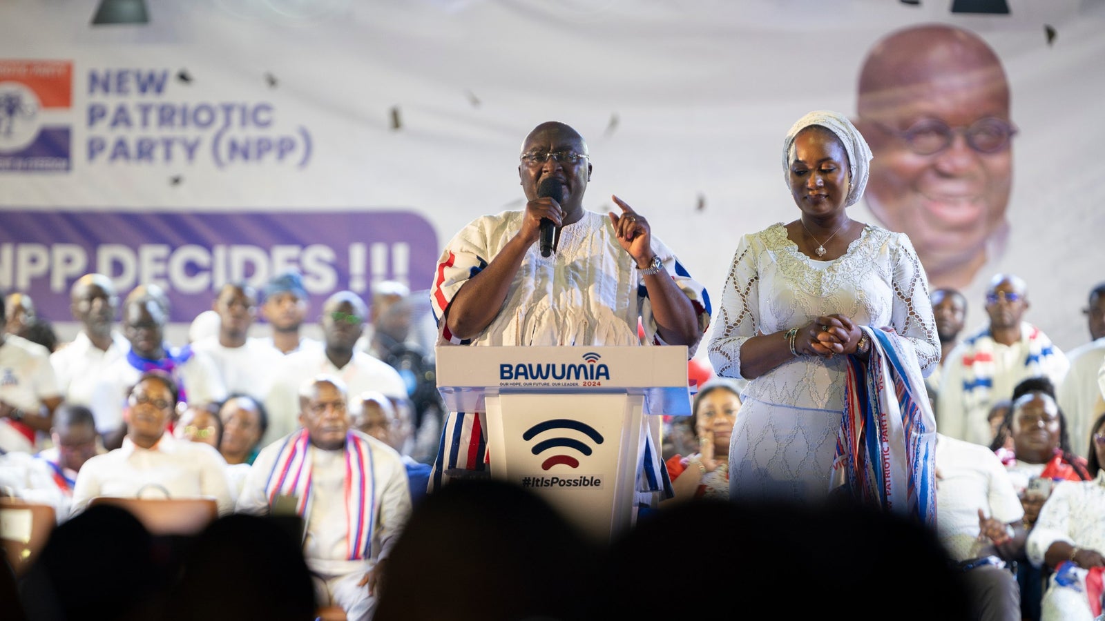 A photo showing Ghana President Mahamudu Bawumia and his wife Samira Bawumia on stage standing behind a podium.