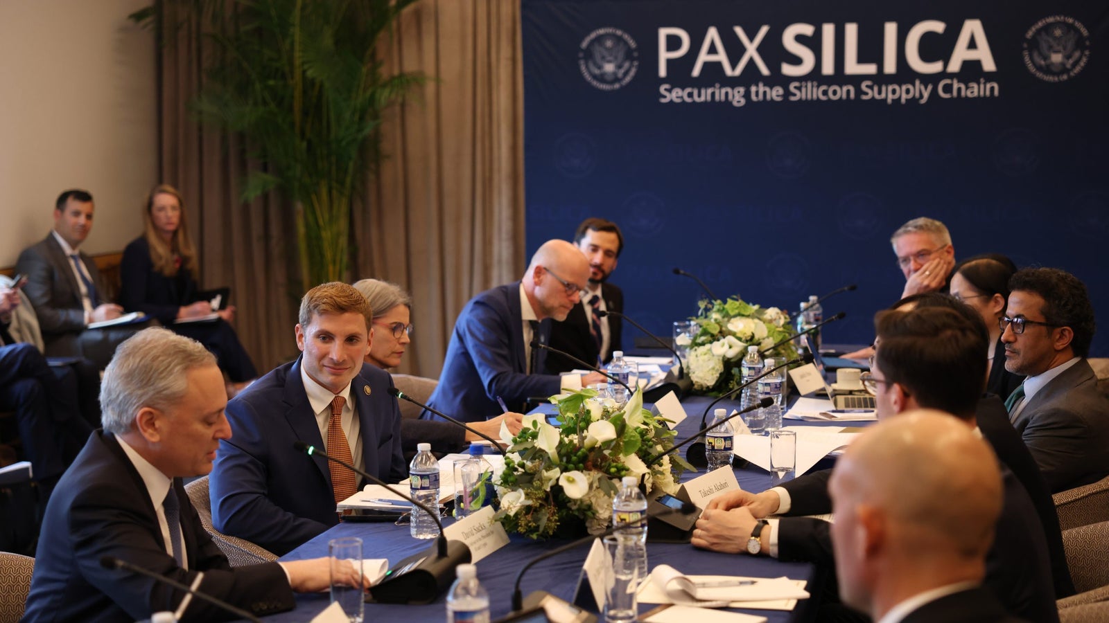 A roundtable discussion on securing the silicon supply chain, featuring various officials and experts seated at a long table.