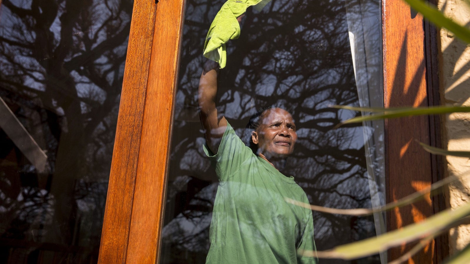 Domestic worker Cynthia Mkovane cleans a glass panel at the house of her employer.