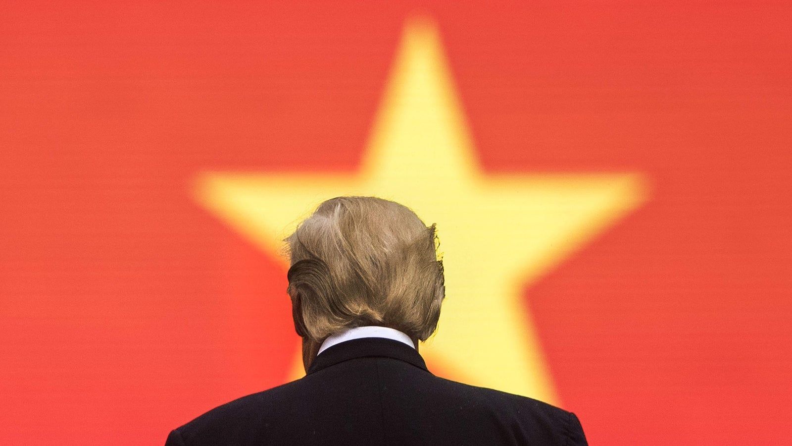 A person with blonde hair facing away, silhouetted against a red background featuring a large yellow star.