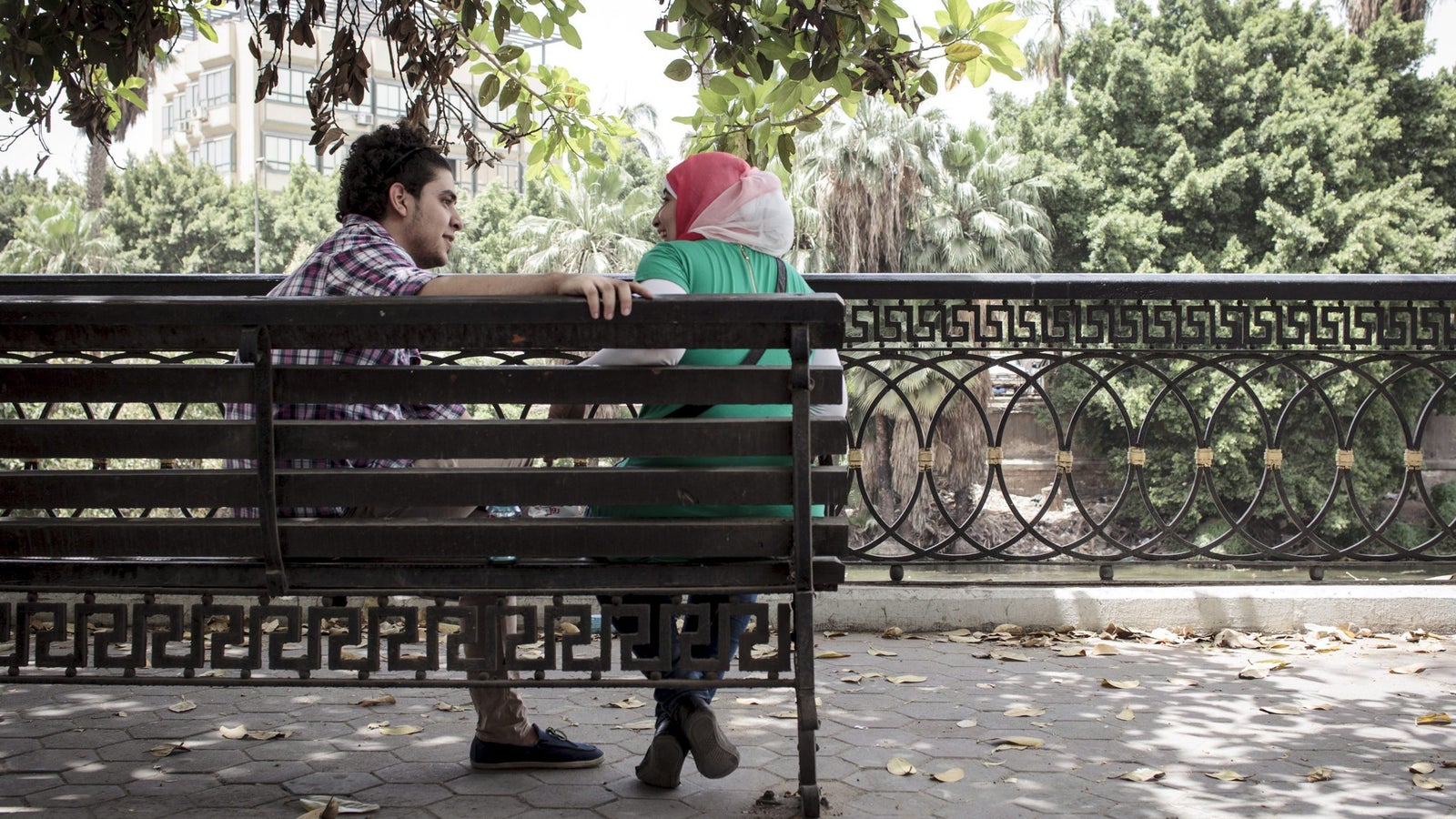 A photo of a man and woman talking to each other on a bench outside