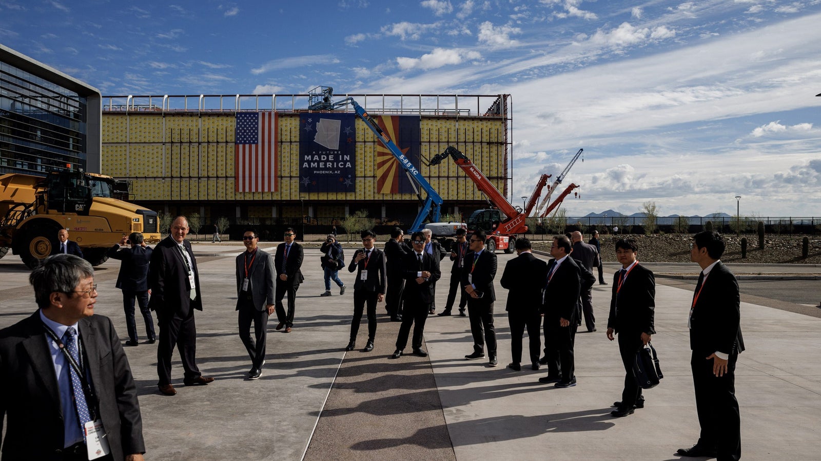 A photo showing a group of people in suits standing outside a large building.