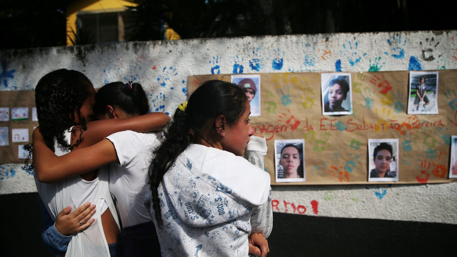 A photo of students crying in front of pictures of the victims shooting at the Raul Brasil school.