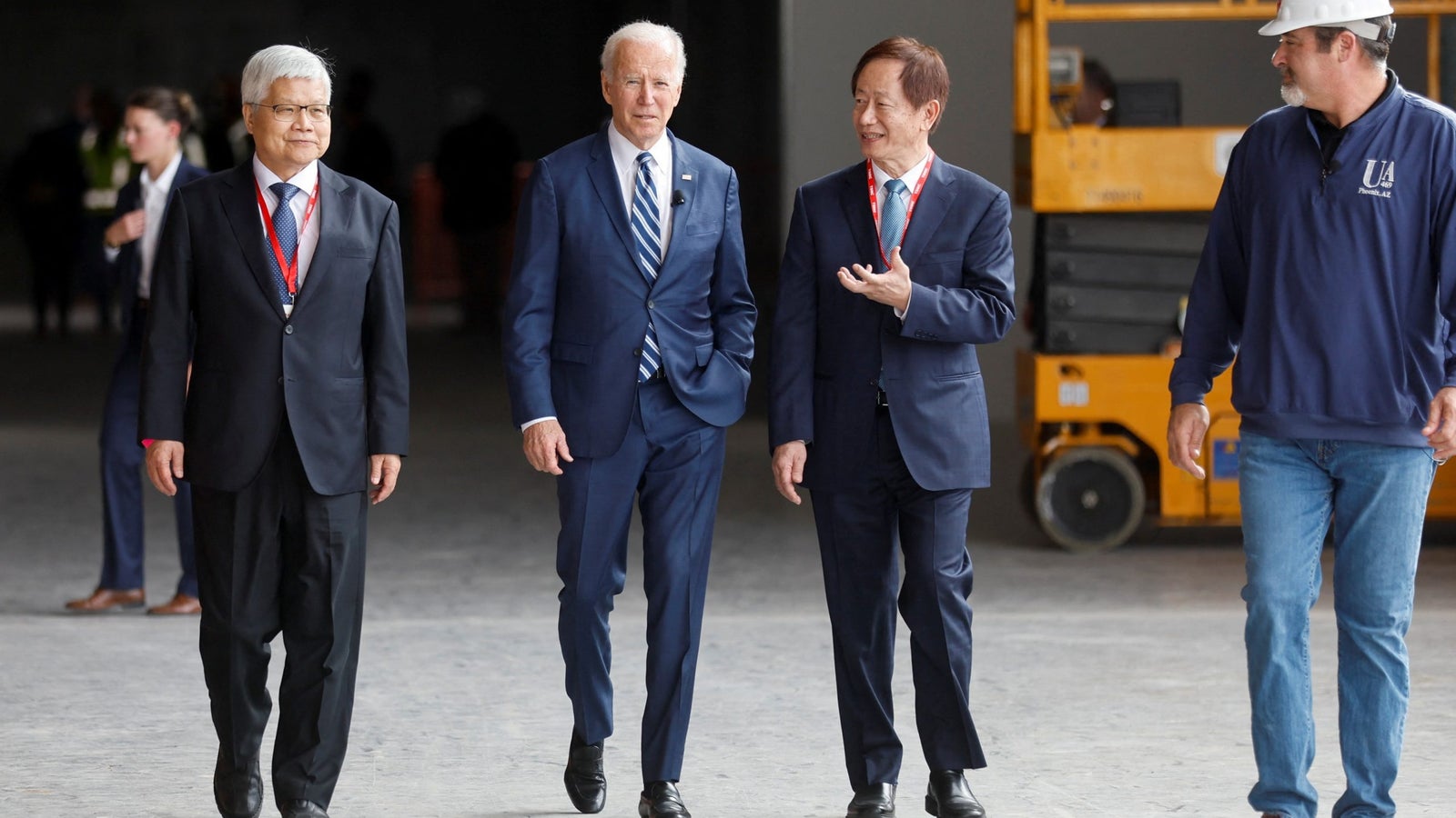 A photograph showing U.S. President Joe Biden walking with with CEO of TSMC C. C. Wei and Chairman of TSMC Mark Liu inside a building.