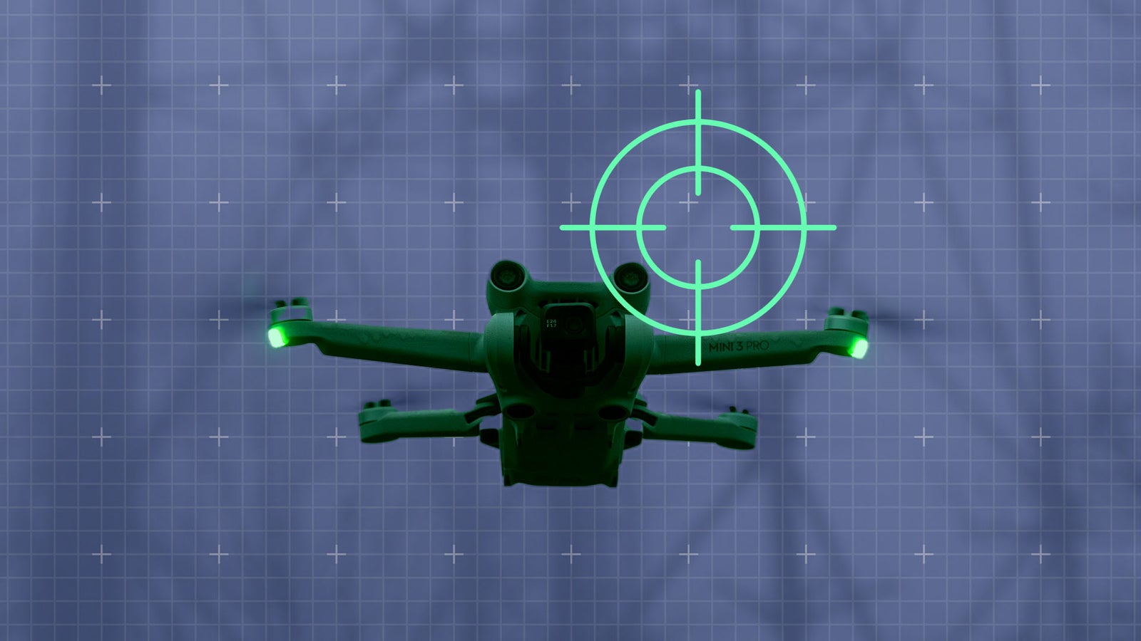 A drone with green illumination is positioned against a blue grid background, featuring a target crosshair overlay aimed at the drone.