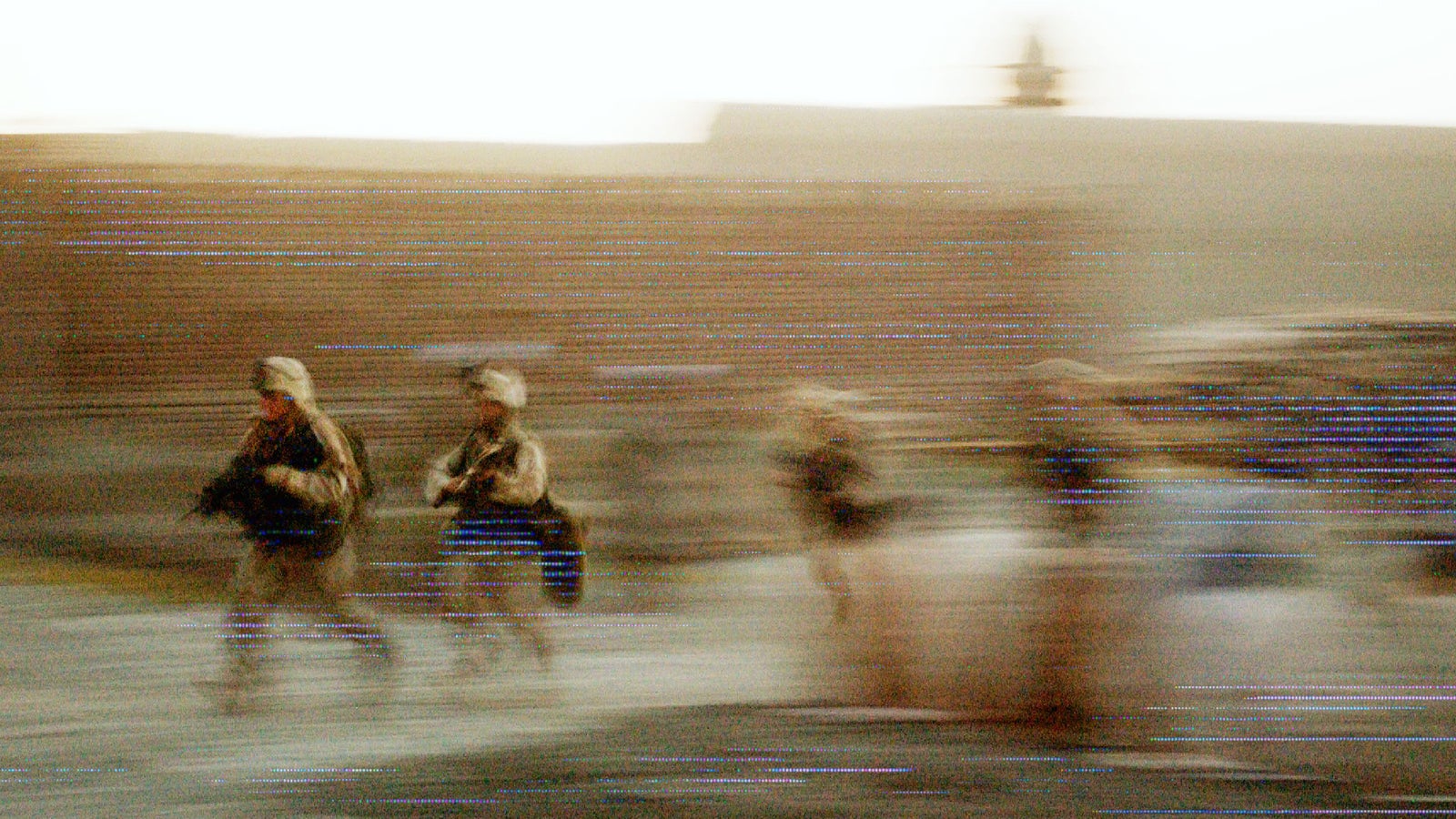 Blurred image of soldiers running, creating a sense of motion with a warm, faded background.