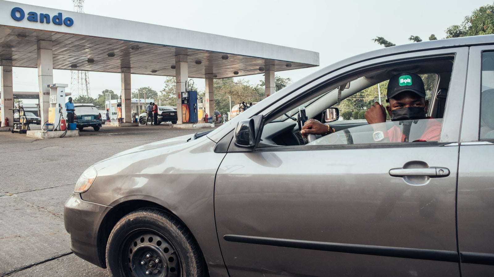 A photo of a Bolt driver sitting in their car at a gas station in Nigeria.