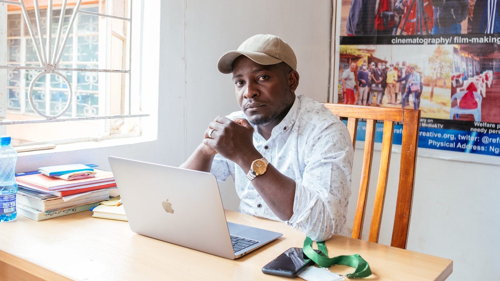 A portrait of Nathan Nkunzimana seated behind his laptop, taken during day time.