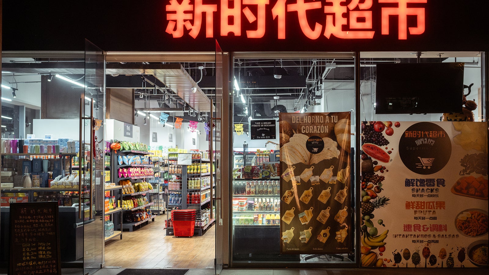 Entrance of a bright store featuring shelves stocked with various snacks and drinks, with signs in Chinese and Spanish.