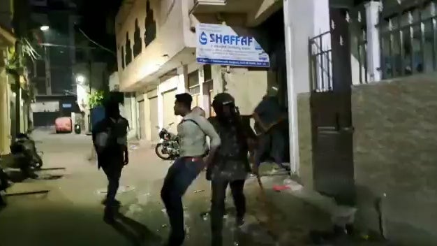 A screenshot from a video showing police officers pulling a man through a street at night.