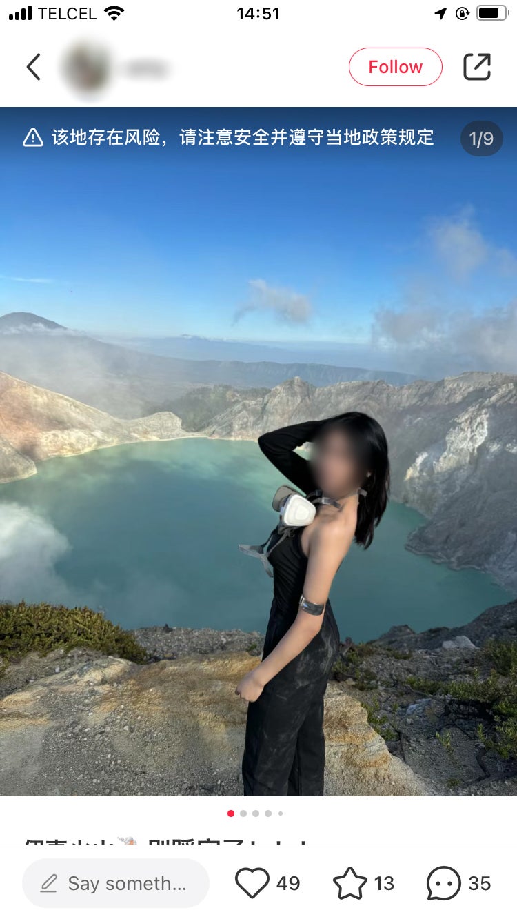 A screenshot from the app Xiahongshou showing a person standing in front of a crater lake. The face is blurred out.