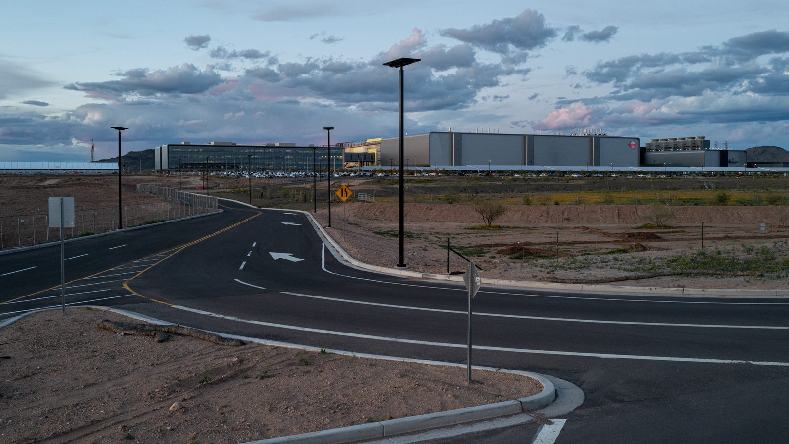 A photograph of a large factory complex and a road leading up to it.